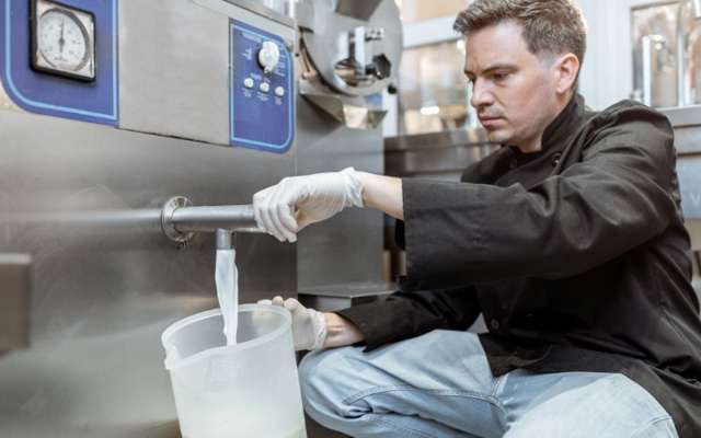 Man pouring milk from a pasteurizer